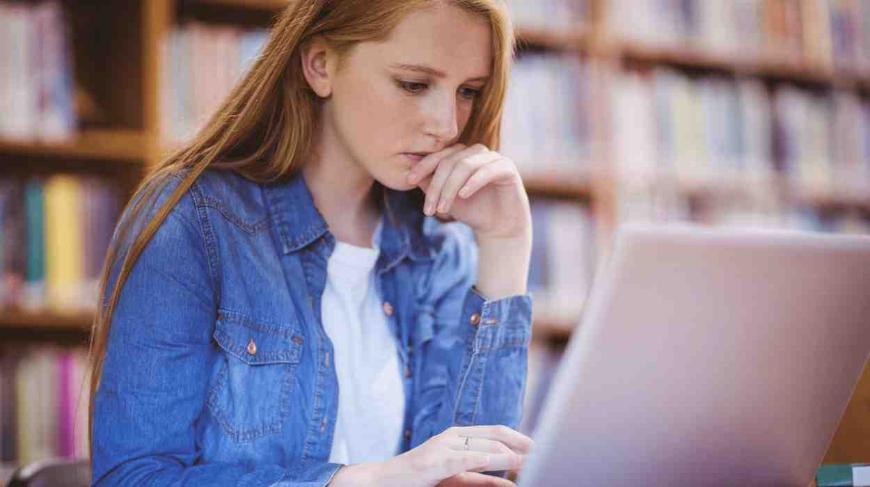 A premed student studying for the MCAT on her laptop in a library.